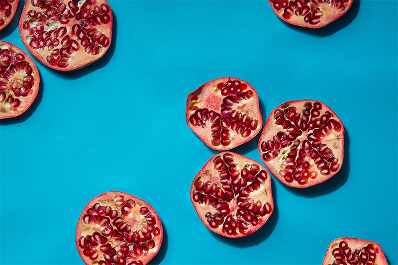 Pomegranates halved and intermittently dispersed on a blue background